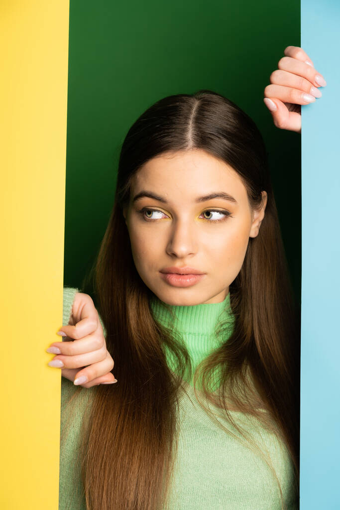 Портрет подростка в свитере, смотрящего в сторону на красочном фоне  - Фото, изображение