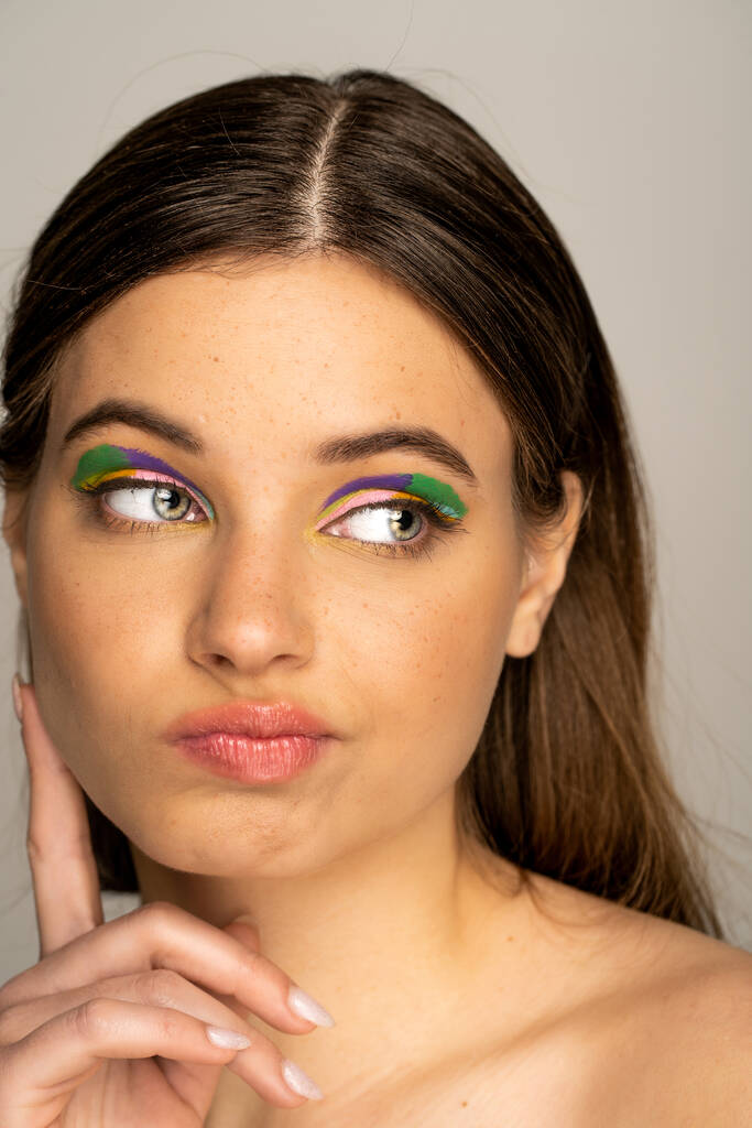 Pensive teenage model with colorful makeup looking away isolated on grey  - Foto, Bild