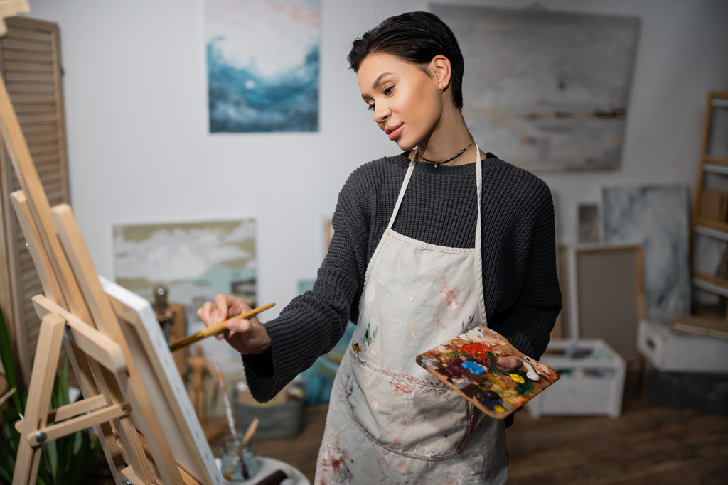 Brunette lyhytkarvainen taiteilija maalaus kankaalle studiossa  - Valokuva, kuva