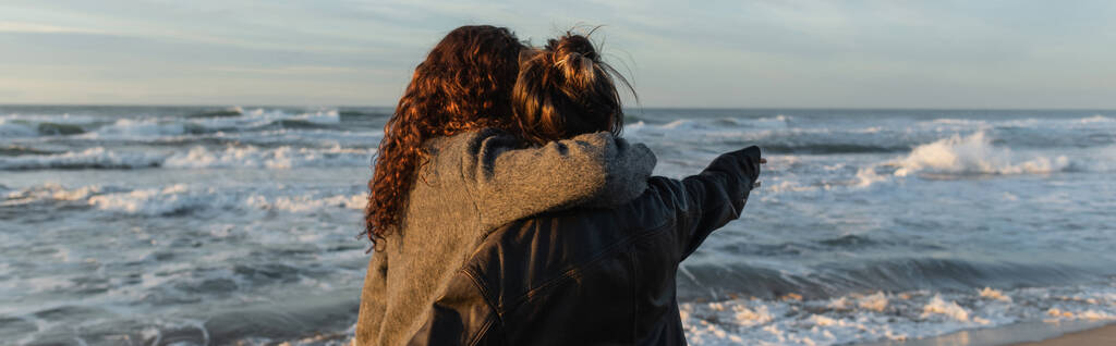Back view of woman hugging friend on beach in Barcelona, banner  - Photo, Image