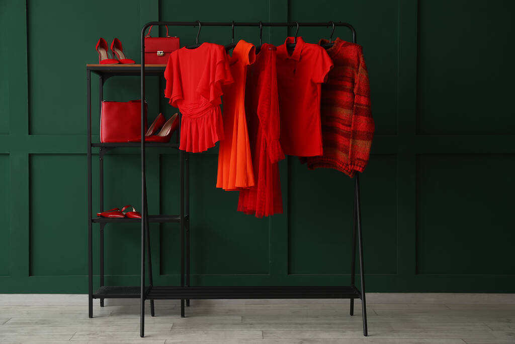 Rack with red clothes, shelving unit and shoes near green wall - Fotoğraf, Görsel