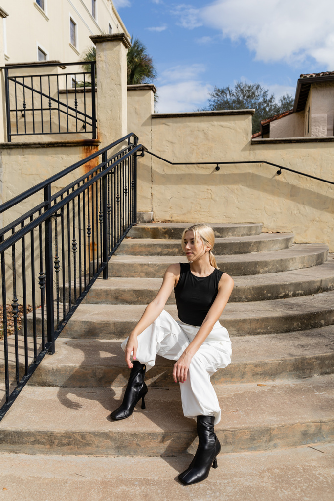 Довга блондинка у модному одязі сидить на сходах біля будинку в Маямі.  - Фото, зображення
