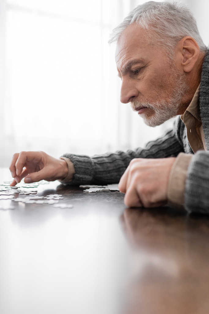 side view of aged man with parkinson syndrome combining jigsaw puzzle at home - Fotoğraf, Görsel