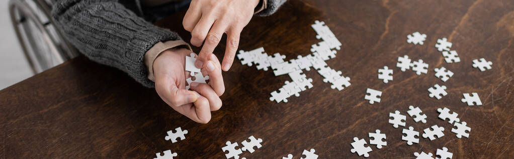 cropped view of man with parkinson syndrome and tremor in hands holding elements of jigsaw puzzle, banner - Foto, Imagem