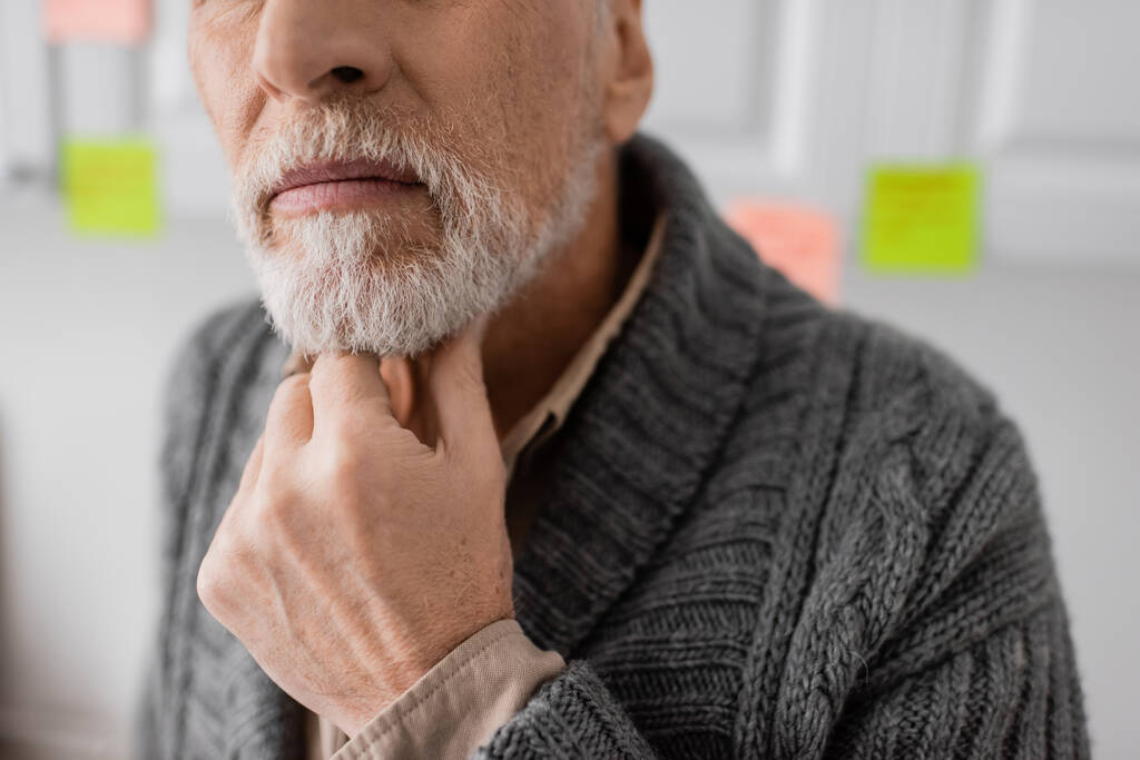cropped view of aged man with alzheimer syndrome thinking and touching beard in kitchen - Foto, immagini