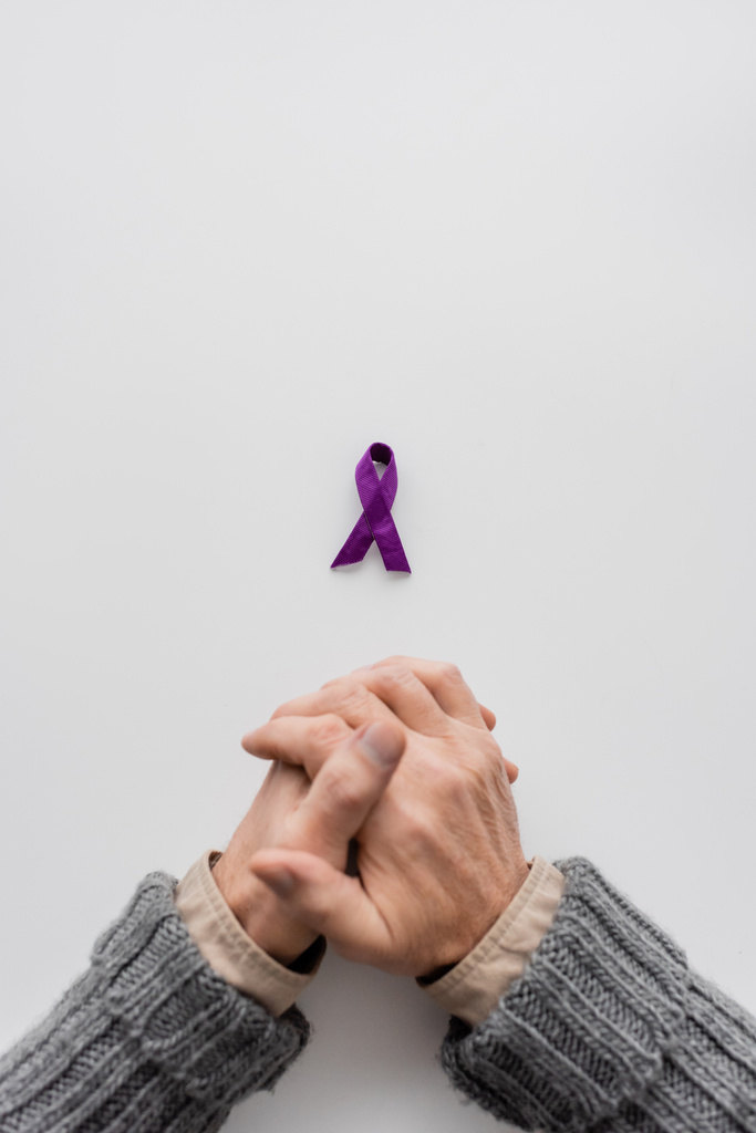 コピースペースのある白い背景に紫アルツハイマー病意識リボン付近のクロップドシニア男性のトップビュー - 写真・画像