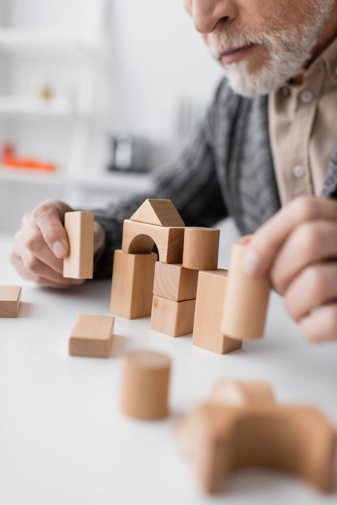 partial view of man with alzheimer disease playing building blocks game on blurred foreground - Foto, Bild