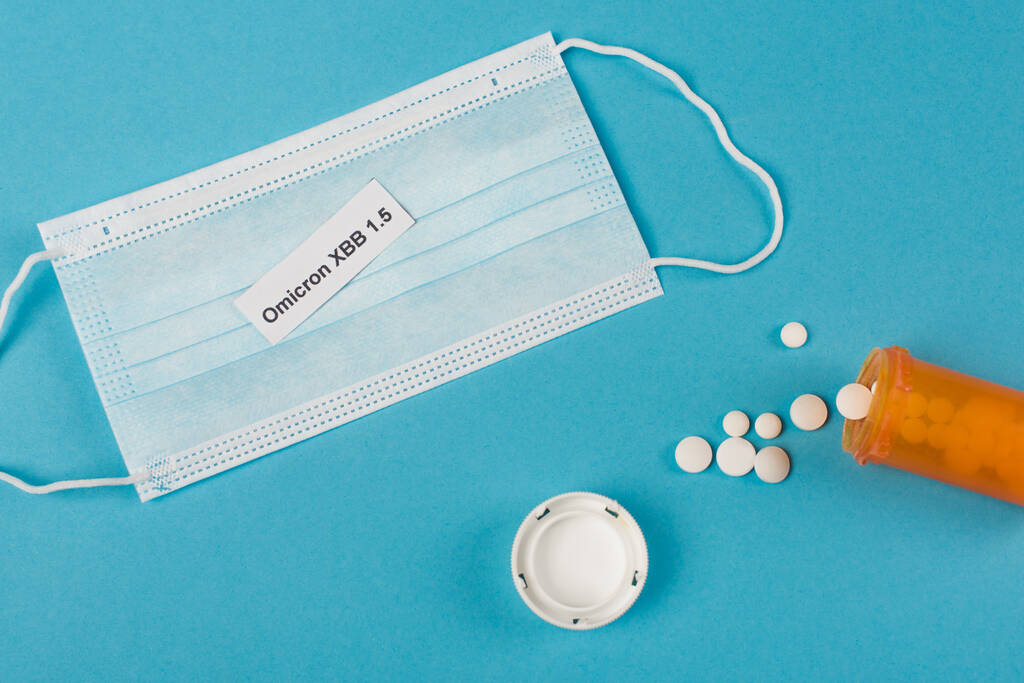 Вид зверху омікрона на медичну маску поблизу таблеток на синьому фоні
  - Фото, зображення