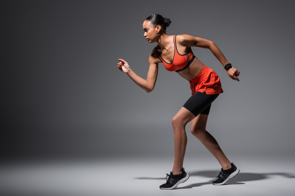 full length of young african american woman in sneakers running on grey  - Fotografie, Obrázek
