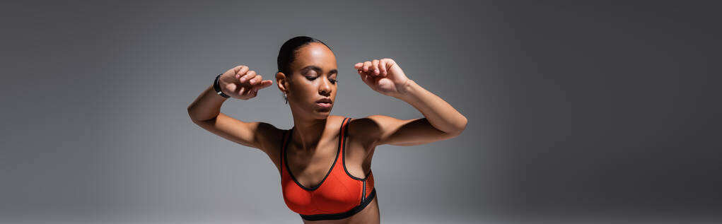 brunette african american woman in sports bra gesturing on grey background, banner  - Φωτογραφία, εικόνα