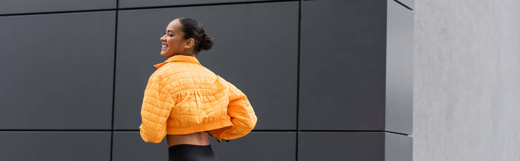 cheerful african american sportswoman in yellow puffer jacket exercising outside, banner  - Foto, Imagem