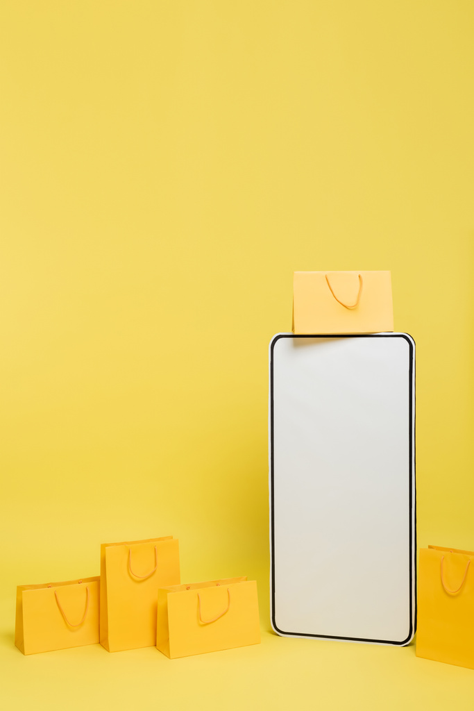 vertical view of huge mock-up of smartphone near shopping bags on yellow background - Valokuva, kuva