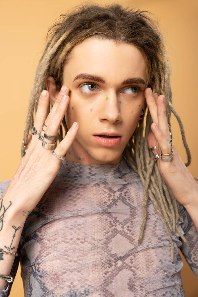 Portrait of queer person with dreadlocks touching face on yellow background  - Zdjęcie, obraz