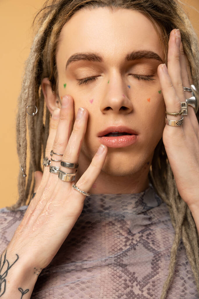Portrait of young queer person with dreadlocks touching face isolated on yellow  - Φωτογραφία, εικόνα