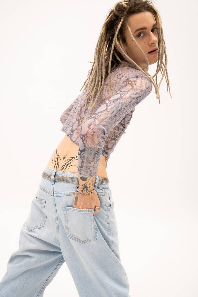 Young queer person with dreadlocks and tattoo posing isolated on white  - Фото, изображение