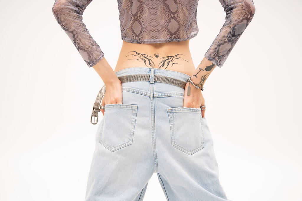 Cropped view of tattooed queer person holding hands in pockets of jeans isolated on white  - Foto, immagini