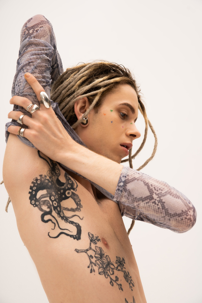 Tattooed queer person in crop top with animal print touching arm isolated on white  - Foto, imagen