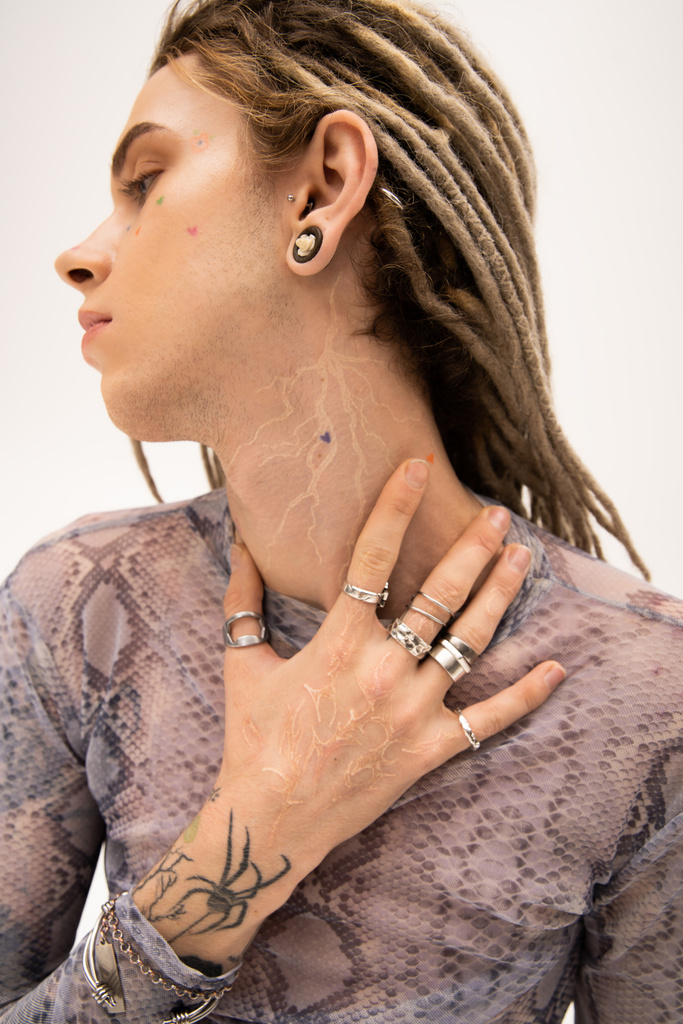 Side view of young tattooed queer person touching neck isolated on white  - Photo, Image