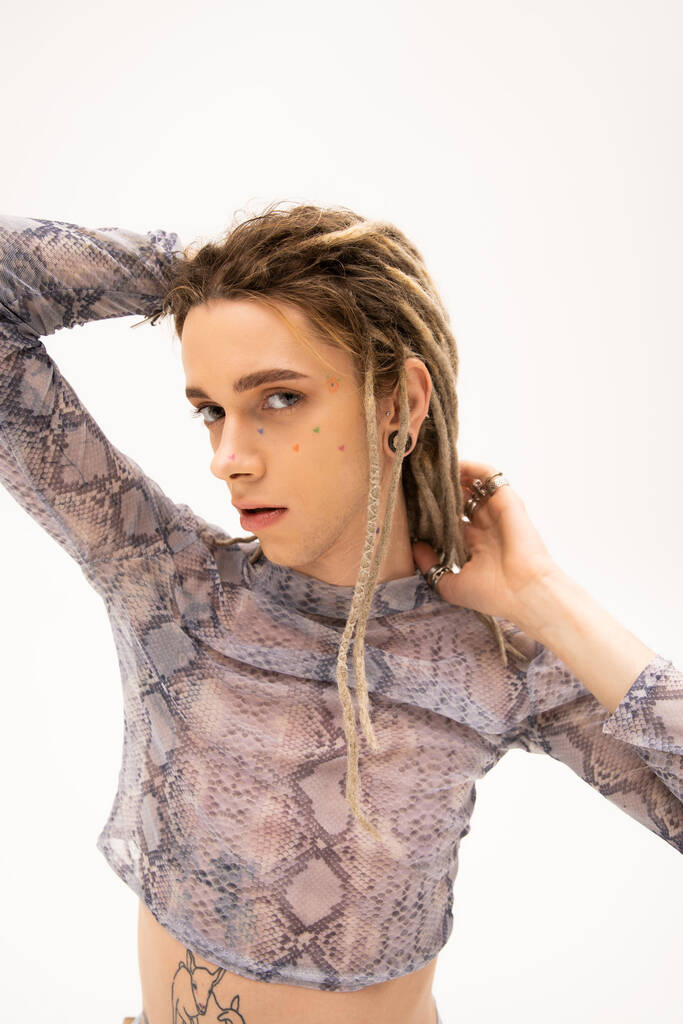 Young tattooed queer person with dreadlocks looking at camera isolated on white  - Zdjęcie, obraz
