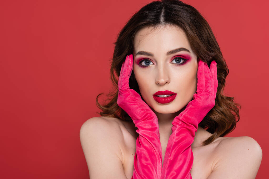 portrait of young woman with magenta color gloves looking at camera isolated on pink  - Foto, Bild