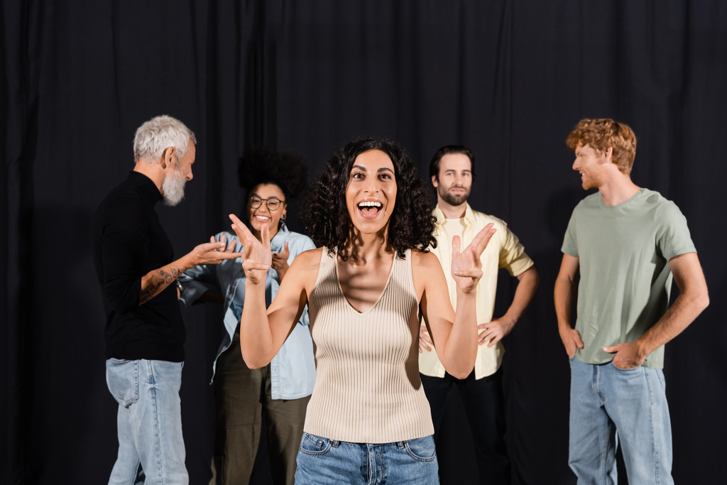 excited multiracial actress rehearsing near young actors and mature screenwriter in theater - Foto, Imagen