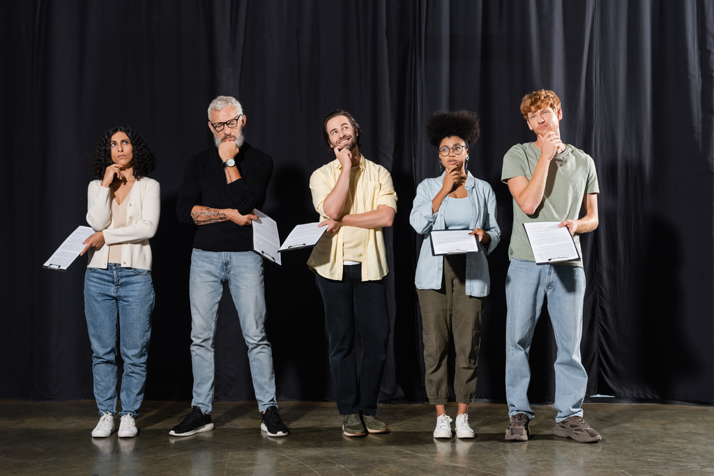 full length of thoughtful multicultural actors with bearded grey haired art director holding scenarios while rehearsing on stage in theater - Photo, Image
