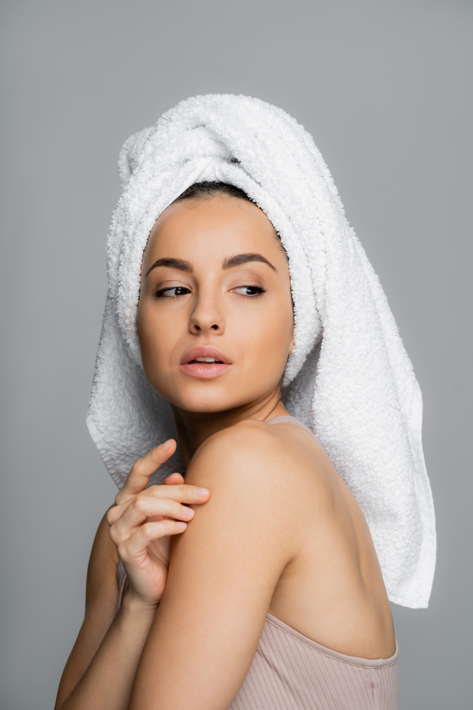 Young woman with towel on hand touching shoulder isolated on grey  - Fotografie, Obrázek
