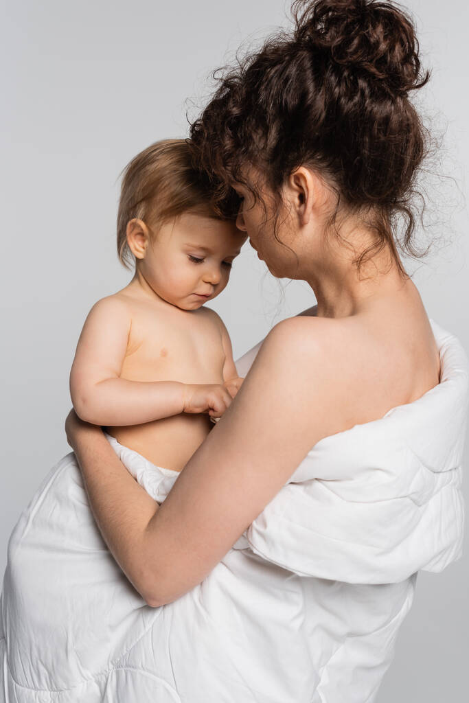 kihara äiti tilalla lapsi tyttö peitetty pussilakana eristetty harmaa  - Valokuva, kuva