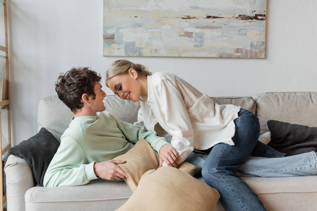 happy young couple laughing while holding pillows in living room  - Foto, immagini