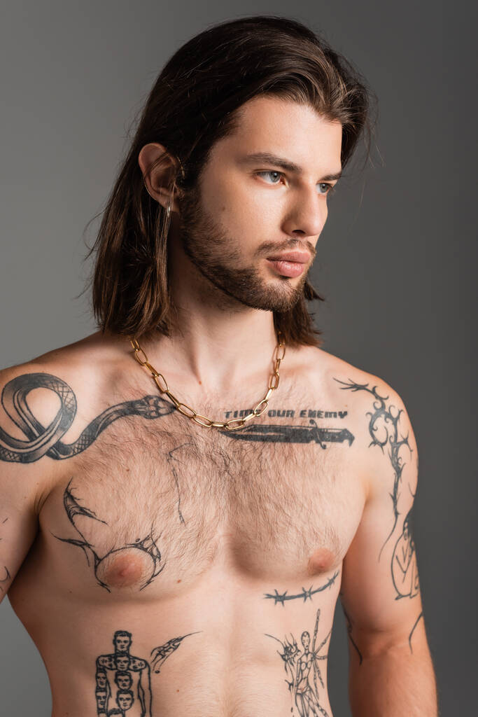 Portrait of shirtless tattooed man looking away isolated on grey  - Foto, imagen