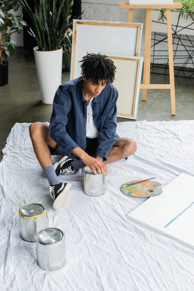 Young african american artist opening jar with paint on workshop  - Photo, Image