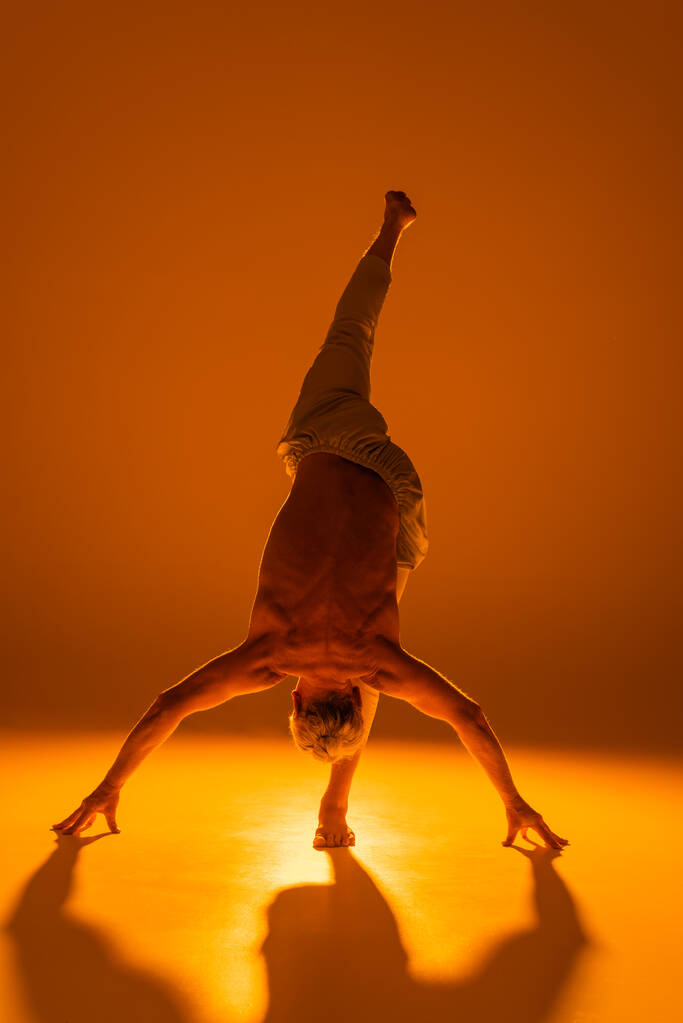 piena lunghezza dell'uomo forte che pratica yoga su sfondo marrone  - Foto, immagini