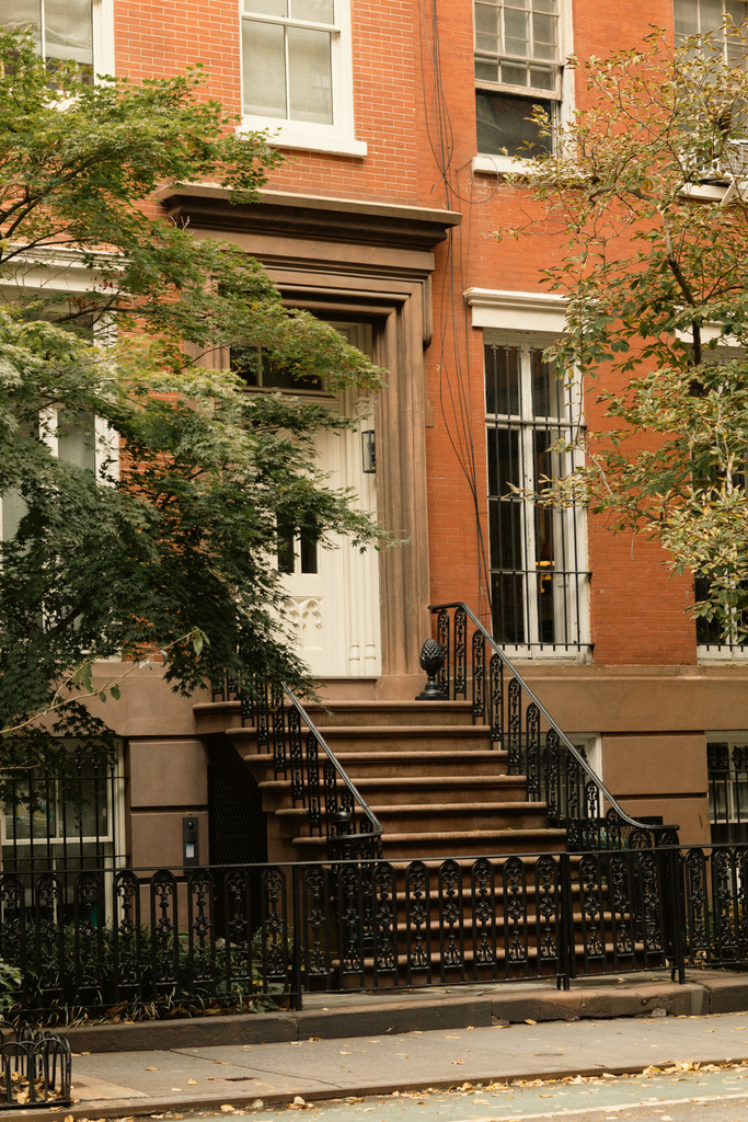 σπίτι από τούβλα με λευκά παράθυρα και είσοδο με σκάλες κοντά στα δέντρα του φθινοπώρου στο δρόμο στη Νέα Υόρκη - Φωτογραφία, εικόνα