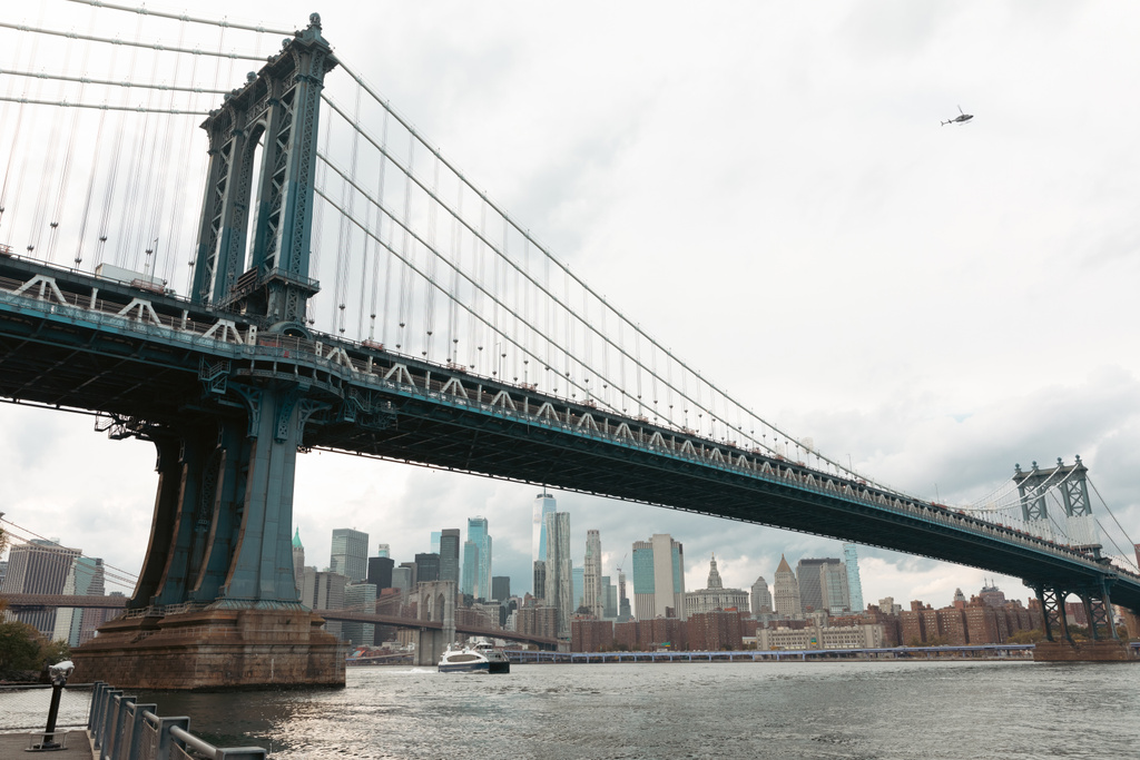scenic view of Manhattan bridge and modern skyscrapers under cloudy sky in New York City - Fotografie, Obrázek