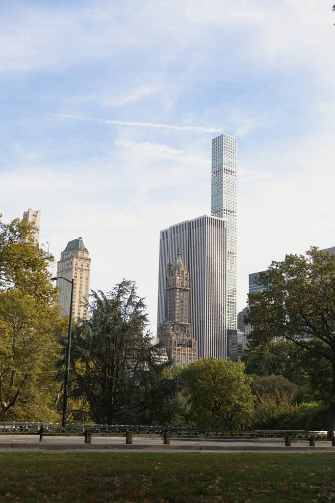 modern skyscrapers near urban park under blue and cloudy sky in New York City - Fotoğraf, Görsel