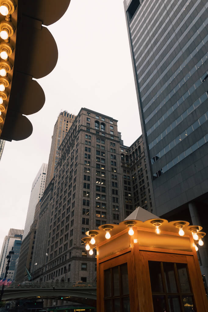 ニューヨークのマンハッタンの夜の街のビルの近くに明るいランプのある電話ブース - 写真・画像