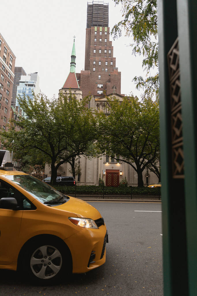 NEW YORK, USA - OCTOBER 13, 2022: yellow taxi car on street with trees and buildings - 写真・画像