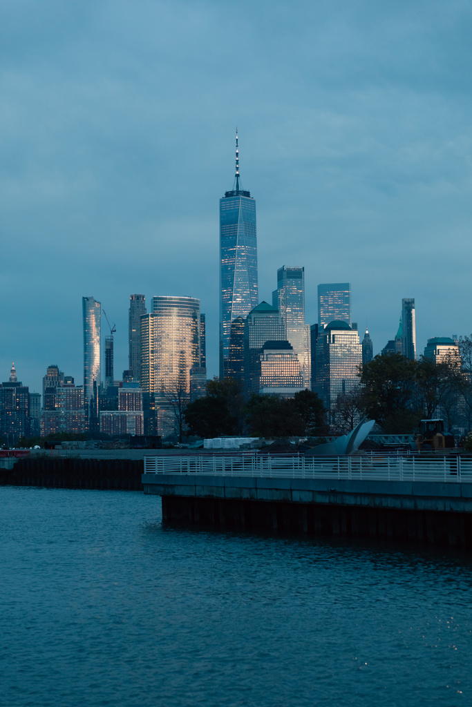 Landschaftliches Stadtbild mit Manhattan-Wolkenkratzern und Pier am Hudson River in der Abenddämmerung - Foto, Bild