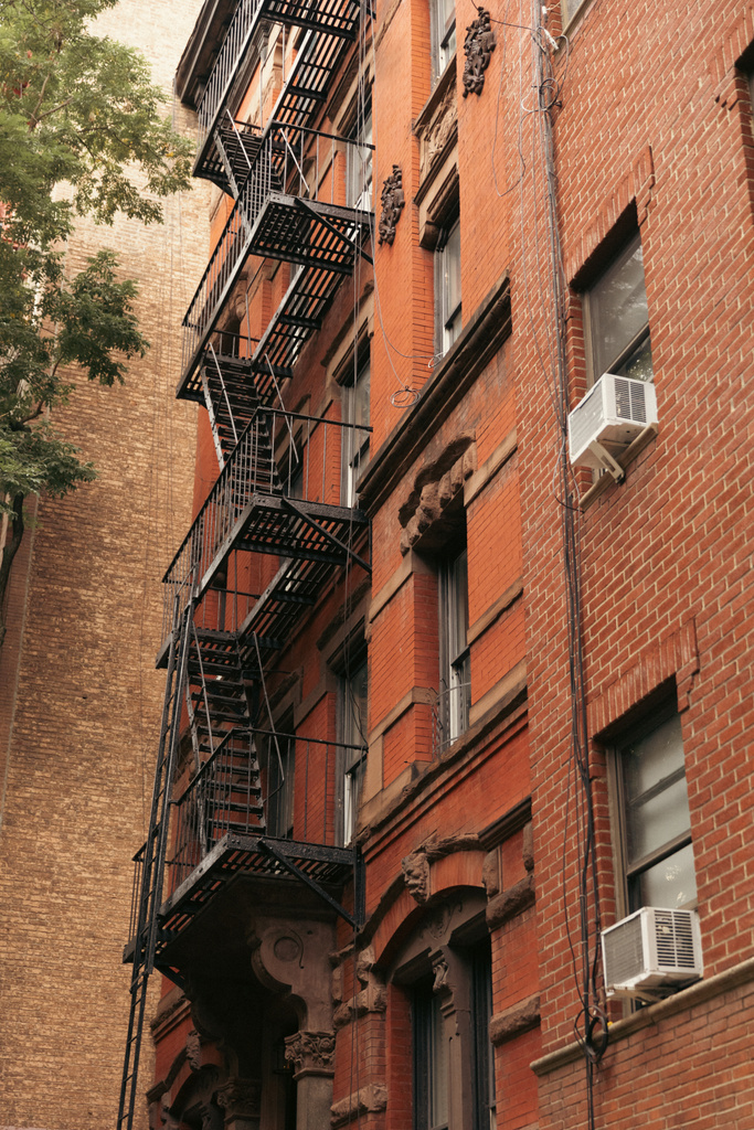 low angle view of brick building with metal balconies and fire escape ladders in New York City - Foto, Imagem