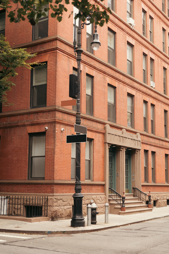 Фонарь с указателями возле здания на городской улице в Нью-Йорке - Фото, изображение