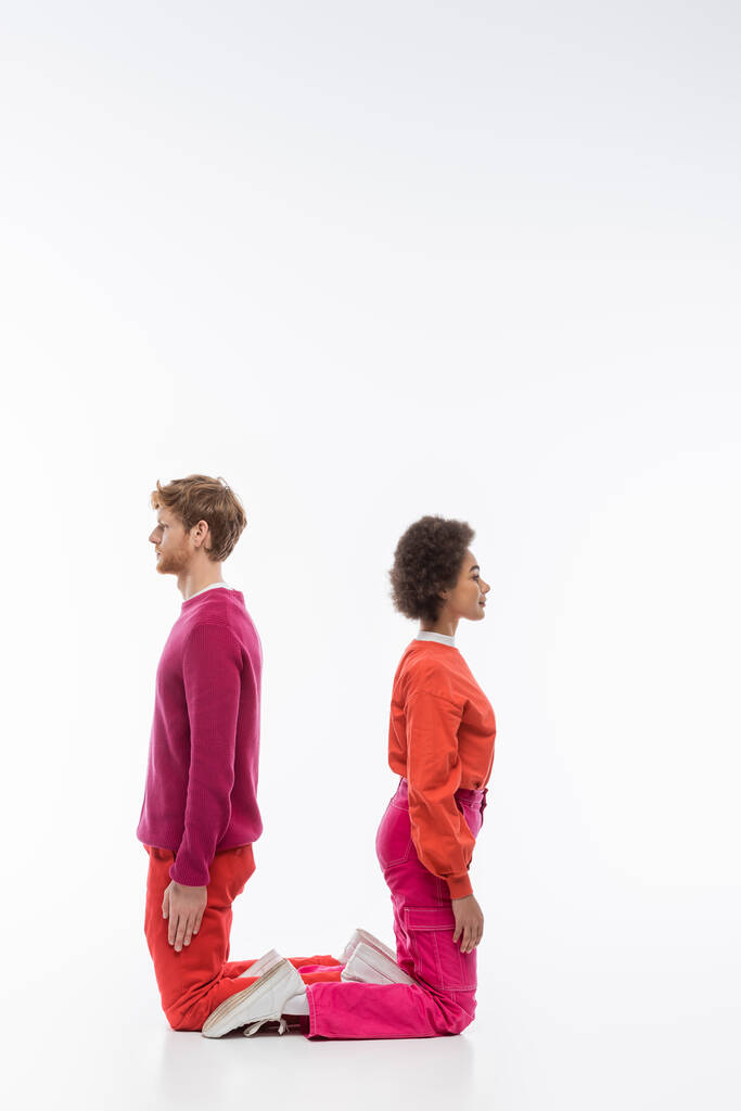 side view of interracial couple in magenta color clothes showing u letter on white background  - Φωτογραφία, εικόνα