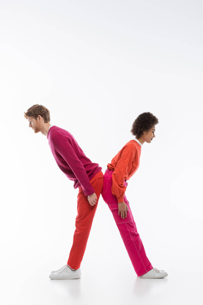 vue latérale du couple interracial en vêtements de couleur magenta montrant x lettre sur fond blanc  - Photo, image