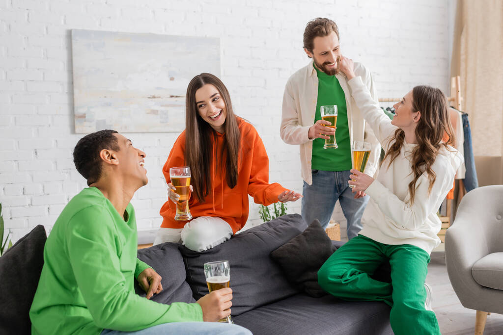 onnellinen monikulttuurinen ystäviä tilalla lasit olutta jutteleminen olohuoneessa  - Valokuva, kuva