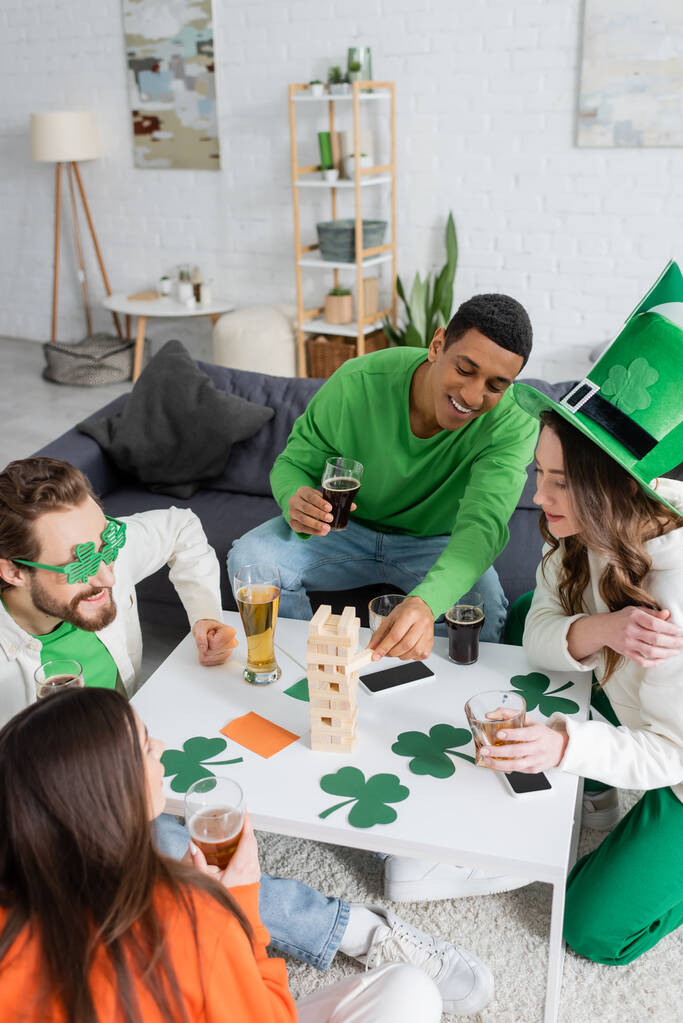 African american man playing wood blocks game with friends during saint patrick day celebration  - Foto, imagen