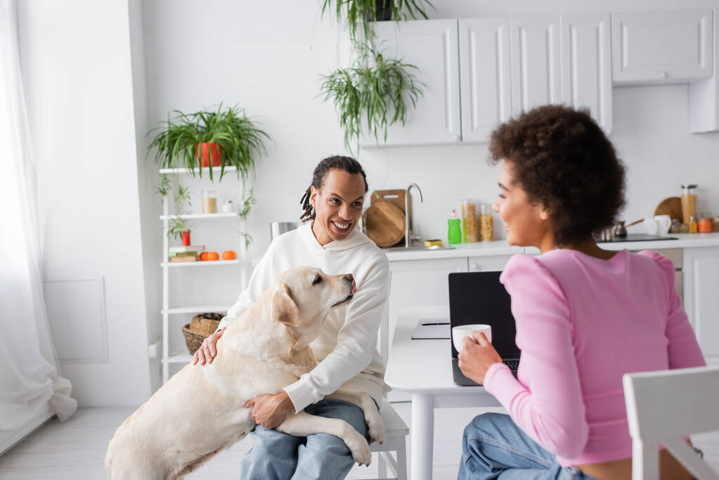 Positive african american couple with labrador talking in kitchen in morning  - Foto, Imagen