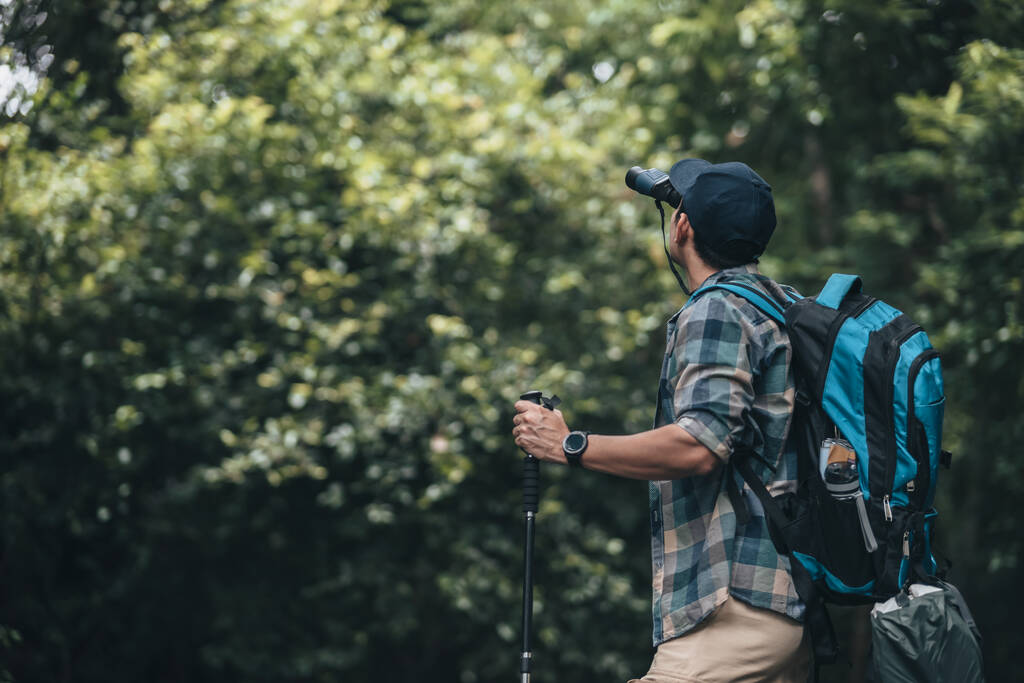 Hikers use binocular to see animals and view landscape  with backpacks walking through on the road in the forest. hiking and adventure concept. - Photo, Image
