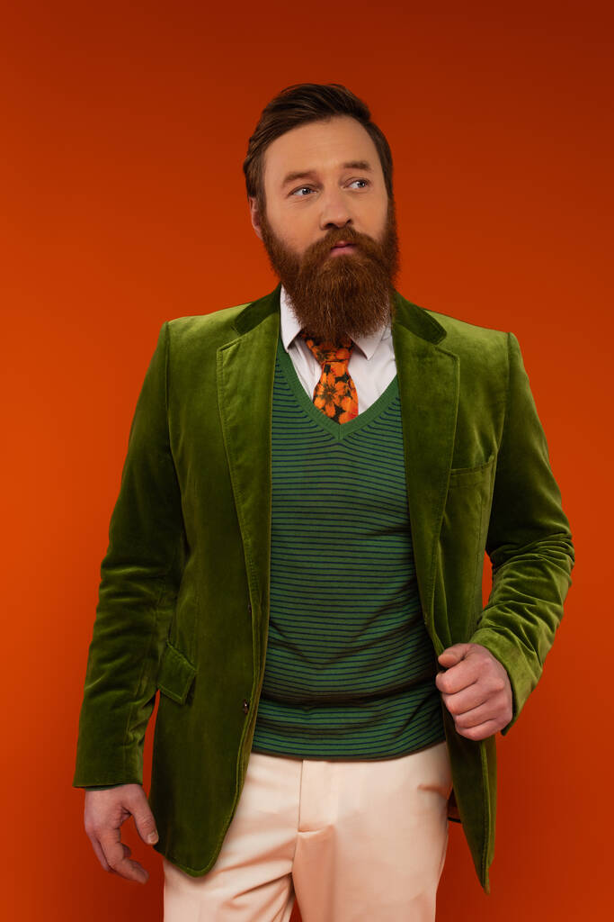Homem elegante em casaco verde posando no fundo vermelho  - Foto, Imagem
