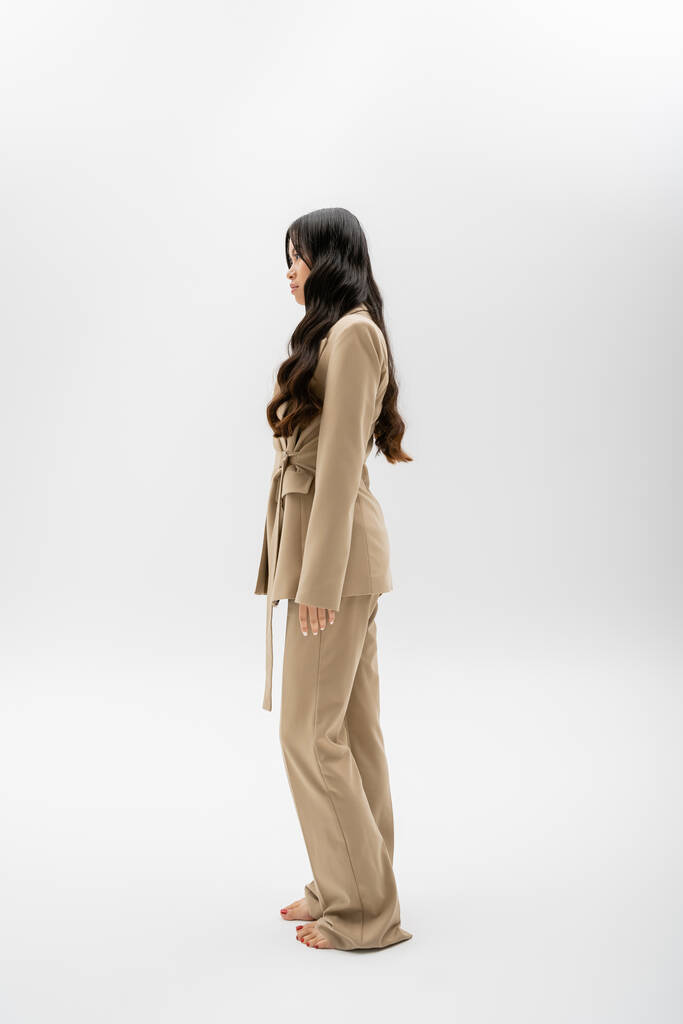 full length of barefoot asian model in fashionable suit standing on grey background - Valokuva, kuva