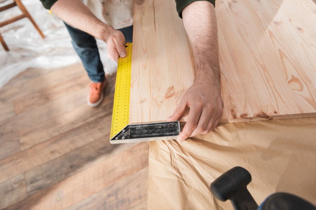 Cropped view of carpenter using square tool on wooden board  - Photo, Image