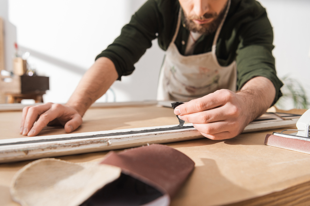 Обрезанный вид ремесленника, восстанавливающего деревянную рамку в мастерской  - Фото, изображение
